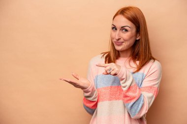 Beyaz tenli genç bir kadın, bej arka planda izole edilmiş. Elinde bir fotokopi odası olduğu için heyecanlı..