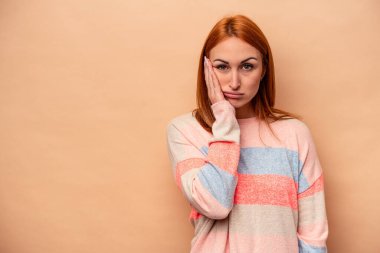 Bej arka planda izole edilmiş, üzgün ve dalgın hisseden, fotokopi alanına bakan beyaz bir kadın..