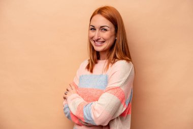 Genç beyaz kadın bej arka planda izole edilmiş mutlu, güler yüzlü ve neşeli..