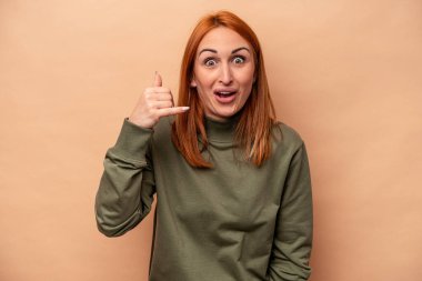 Beyazlı genç bir kadın bej arka planda izole edilmiş bir şekilde bir şeye gülüyor, ağızlarını elleriyle kapatıyor..