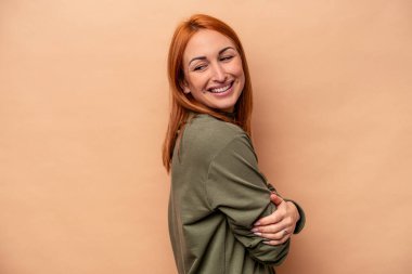 Genç beyaz kadın bej arka planda izole edilmiş gülüyor ve eğleniyor..