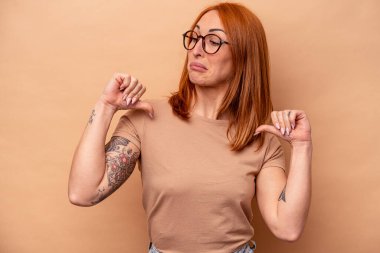 Bej arka planda izole edilmiş genç beyaz kadın gururlu ve kendinden emin hissediyor, örnek olarak.