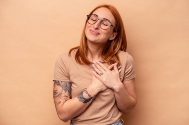 Bej arka planda izole edilmiş beyaz bir kadın. Dostane bir ifadeye sahip. Avuçlarını göğsüne bastırıyor. Aşk konsepti.