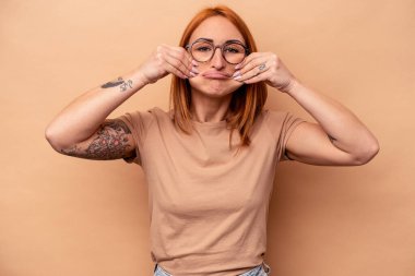 Beyaz tenli genç bir kadın bej arka planda izole edilmiş. İki seçenek arasında şüpheyle bakıyor..