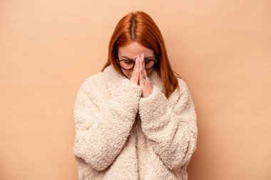 Beyaz tenli genç bir kadın bej arka planda izole edilmiş dua ediyor, bağlılık gösteriyor, dindar biri ilahi ilham arıyor..