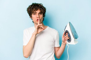 Mavi arka planda demir tutan genç beyaz adam bir sır saklıyor ya da sessizlik istiyor..