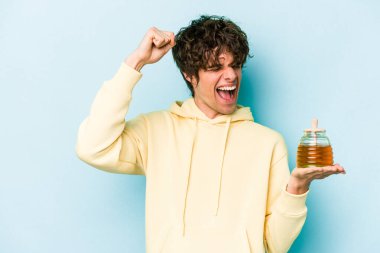 Mavi arka planda bal tutan beyaz bir adam zafer kazandıktan sonra yumruğunu kaldırıyor..