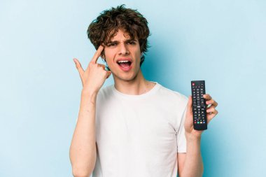 Mavi arka planda televizyon kumandası tutan beyaz bir adam işaret parmağıyla yaptığı hayal kırıklığı jestini gösteriyor..