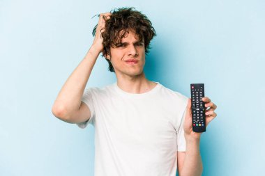 Elinde televizyon kumandası olan beyaz bir adam mavi arka planda izole edilmiş, şoka uğramış, önemli bir toplantıyı hatırlıyor..