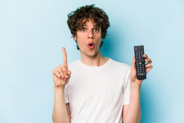 Elinde televizyon kumandası olan beyaz bir adam mavi arka planda izole edilmiş. Harika bir fikri var, yaratıcılık kavramı..