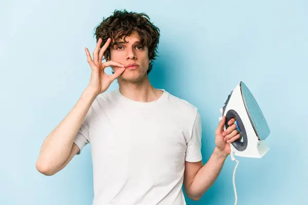 Young Caucasian Man Holding Iron Isolated Blue Background Fingers Lips — Stock Photo, Image