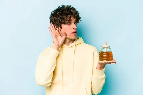 Jonge Blanke Man Met Honing Geïsoleerd Blauwe Achtergrond Proberen Een — Stockfoto
