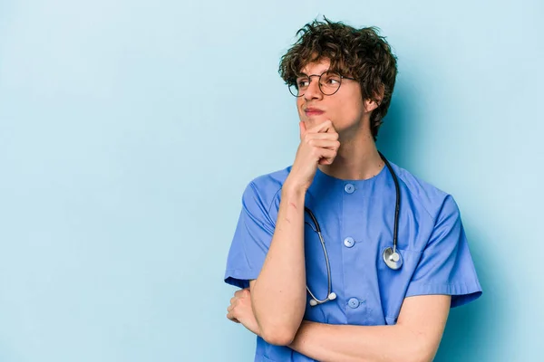Jonge Blanke Verpleegkundige Man Geïsoleerd Blauwe Achtergrond Kijken Zijwaarts Met — Stockfoto
