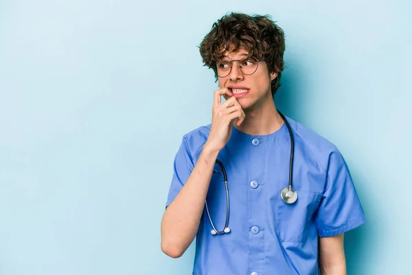 Jonge Blanke Verpleegkundige Man Geïsoleerd Blauwe Achtergrond Ontspannen Denken Iets — Stockfoto