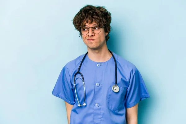 Jonge Kaukasische Verpleegkundige Man Geïsoleerd Blauwe Achtergrond Verward Voelt Twijfelachtig — Stockfoto