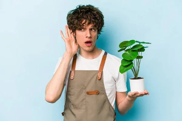 Jovem Jardineiro Caucasiano Homem Segurando Uma Planta Isolada Fundo Azul — Fotografia de Stock