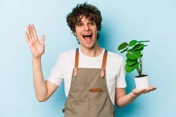 Jovem Jardineiro Caucasiano Homem Segurando Uma Planta Isolada Fundo Azul — Fotografia de Stock