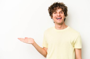 Beyaz arka planda izole edilmiş genç beyaz bir adam bir palmiye üzerinde fotokopi alanı gösteriyor ve belinde başka bir el tutuyor..