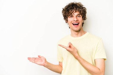 Beyaz arka planda izole edilmiş genç beyaz bir adam, palmiye üzerinde bir fotokopi alanı tutarken heyecanlı..