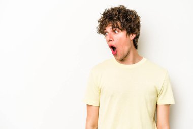 Beyaz arka planda izole edilmiş genç beyaz adam gördüğü bir şey yüzünden şoka uğruyor..