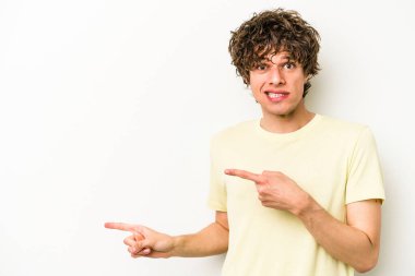 Beyaz arka planda izole edilmiş genç beyaz bir adam işaret parmağıyla fotokopi alanını işaret ederek şok oldu..