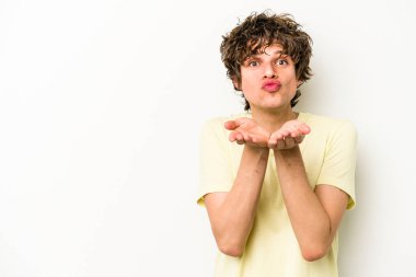 Beyaz arka planda izole edilmiş genç beyaz bir adam dudaklarını katlıyor ve hava öpücüğü vermek için avuç içleri tutuyor..