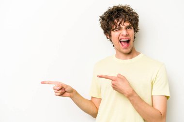 Beyaz arka planda izole edilmiş genç beyaz bir adam işaret parmağıyla fotokopi alanını işaret ederek heyecan ve arzusunu ifade ediyor..