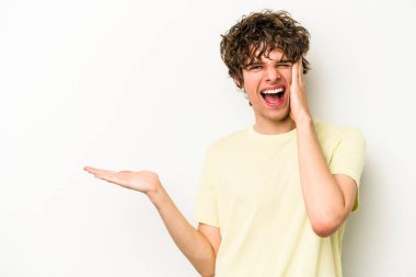 Beyaz arka planda izole edilmiş genç beyaz bir adam bir avuç içinde fotokopi alanı tutuyor, el üstünde tutuyor. Şaşırmış ve mutlu..