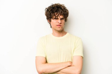 Beyaz arka planda izole edilmiş, hoşnutsuzca kaşlarını çatmış, kollarını kavuşturmuş genç beyaz bir adam..