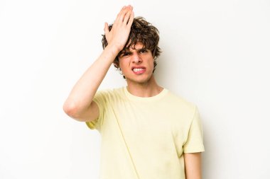 Beyaz arka planda izole edilmiş genç beyaz bir adam bir şeyi unutuyor. Alnına avuç içi ve gözlerini kapayarak vuruyor..