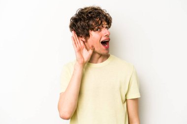 Beyaz arka planda izole edilmiş genç beyaz adam bir dedikoduyu dinlemeye çalışıyor..