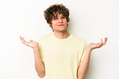 Beyaz arka planda izole edilmiş genç beyaz bir adam sorgulama sırasında omuz silkiyor ve şüphe duyuyor..