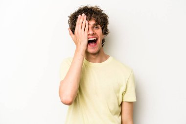 Beyaz arka planda izole edilmiş genç beyaz bir adam yüzünün yarısını palmiye ile örterek eğleniyor..