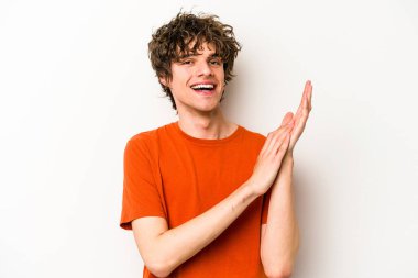 Beyaz arka planda izole olmuş genç beyaz bir adam enerjik ve rahat hissediyor, ellerini ovuşturuyor..