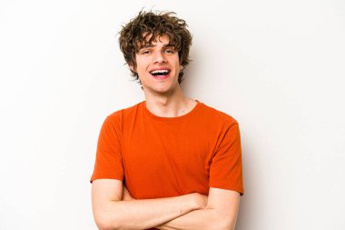 Beyaz arka planda kendini güvende hisseden, kararlılıkla kollarını kavuşturan beyaz tenli genç bir adam..