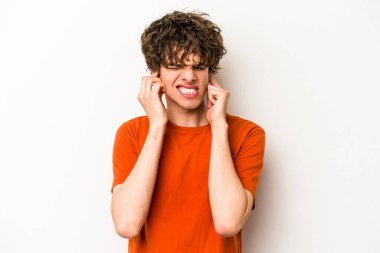 Beyaz arka planda izole edilmiş genç beyaz bir adam kulaklarını elleriyle kapatıyor..