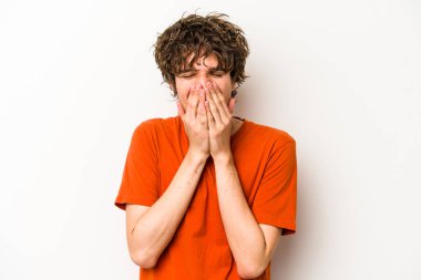 Beyaz arka planda izole olmuş genç beyaz bir adam bir şeye gülüyor, ağızlarını ellerle kapatıyor..