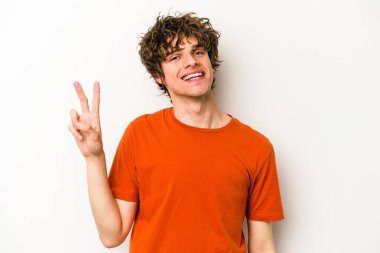 Beyaz arka planda izole edilmiş genç beyaz bir adam neşeli ve kaygısız parmakları olan bir barış sembolü gösteriyor..