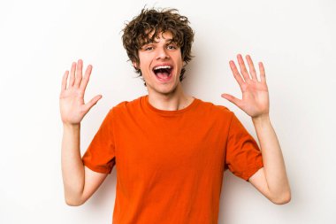 Beyaz arka planda izole edilmiş beyaz tenli genç adam on numarayı elleriyle gösteriyor..