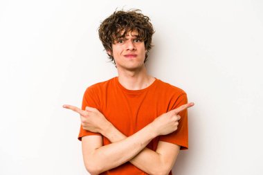 Beyaz arka plan noktalarında izole genç beyaz adam, iki seçenek arasında seçim yapmaya çalışıyor.