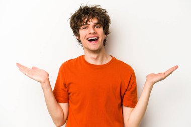 Beyaz arka planda izole genç beyaz adam kollarıyla ölçek yapar, mutlu ve kendinden emin hisseder..