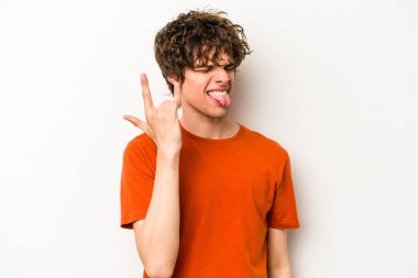 Beyaz arka planda izole edilmiş genç beyaz bir adam parmaklarıyla kaya hareketi gösteriyor.