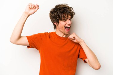 Beyaz arka planda izole genç beyaz adam özel bir günü kutluyor, atlıyor ve enerjiyle kollarını kaldırıyor..