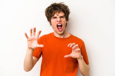 Beyaz arka planda izole edilmiş genç beyaz bir adam pençelerini kedi taklidi yaparken gösteriyor, agresif bir hareket..