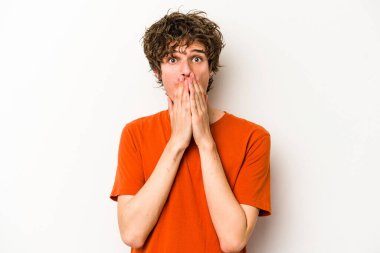 Beyaz arka planda izole edilmiş genç beyaz adam şok olmuş, ağzı ellerle kaplanmış, yeni bir şey keşfetmeye hevesli..