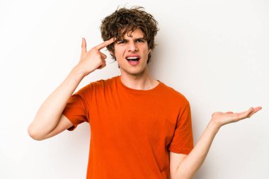 Beyaz arka planda izole edilmiş genç beyaz bir adam elinde bir ürün tutuyor ve.