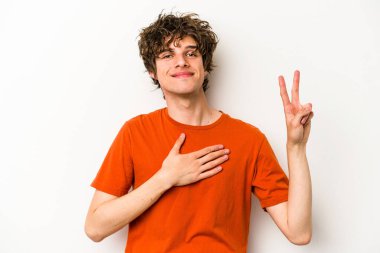 Beyaz arka planda izole edilmiş genç beyaz adam yemin ediyor, elini göğsüne koyuyor..