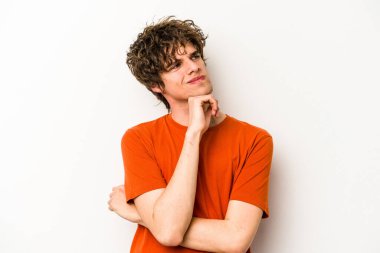 Beyaz arka planda soyutlanmış genç beyaz bir adam düşünüyor ve yukarı bakıyor, yansıtıyor, düşünüyor, hayal kuruyor..