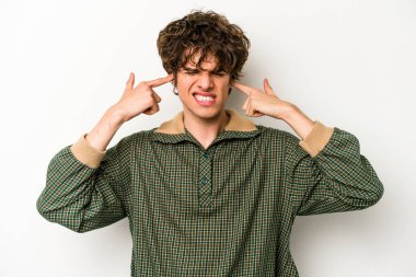 Beyaz arka planda izole edilmiş genç beyaz bir adam parmaklarıyla kulaklarını kapatıyor, gürültülü bir ortam yüzünden stresli ve çaresiz..