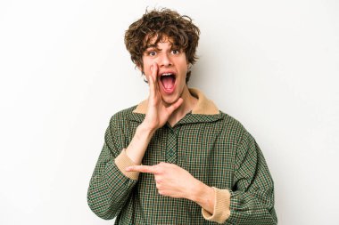 Beyaz arka planda izole edilmiş genç beyaz bir adam bir dedikodu söylüyor, bir haber sunuyor..